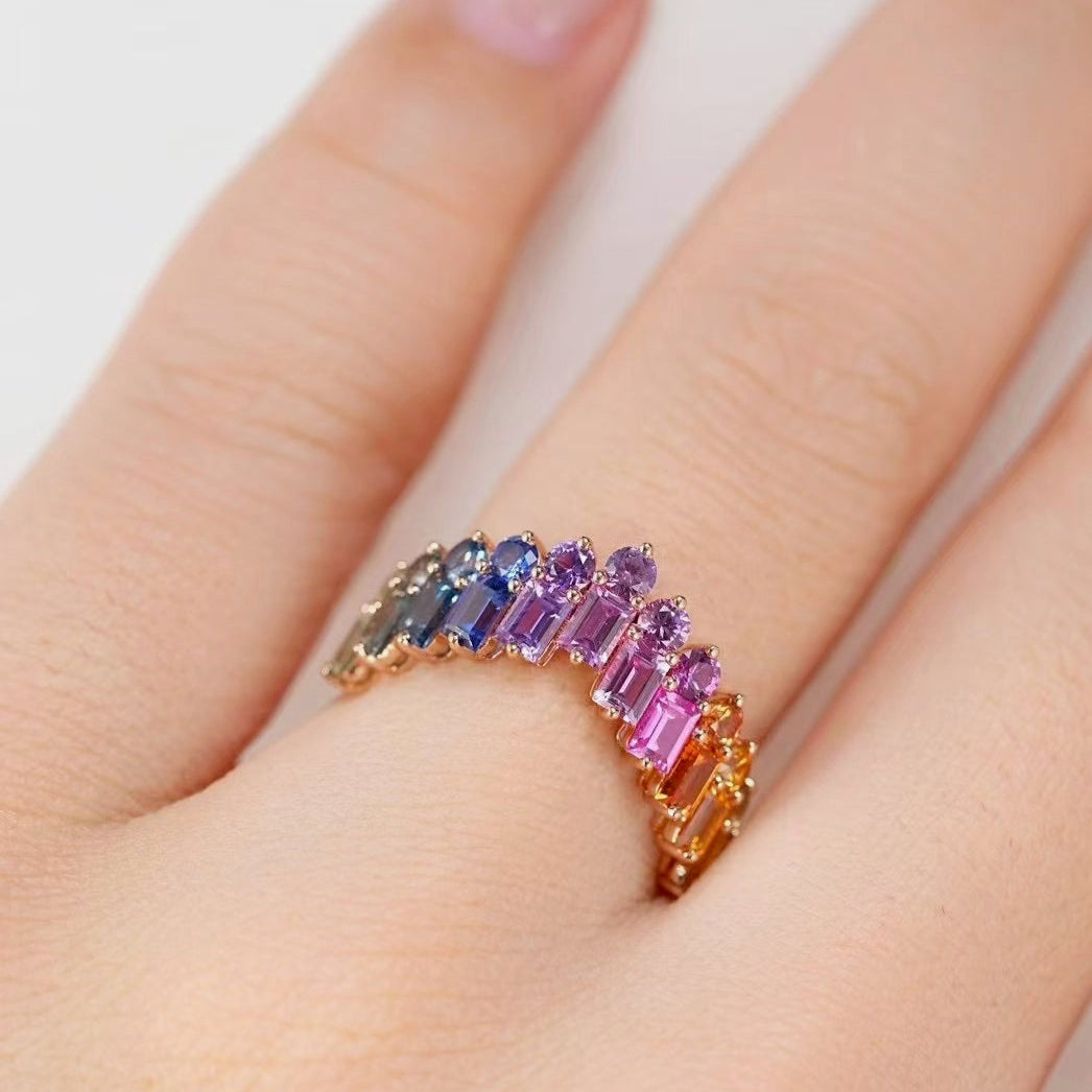 Ring with multicolored gemstones on a finger against a white background