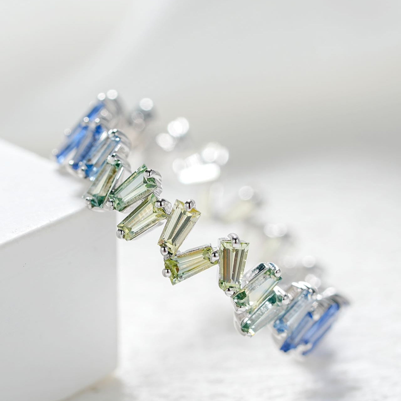 Earring with green and blue gemstones on a white background