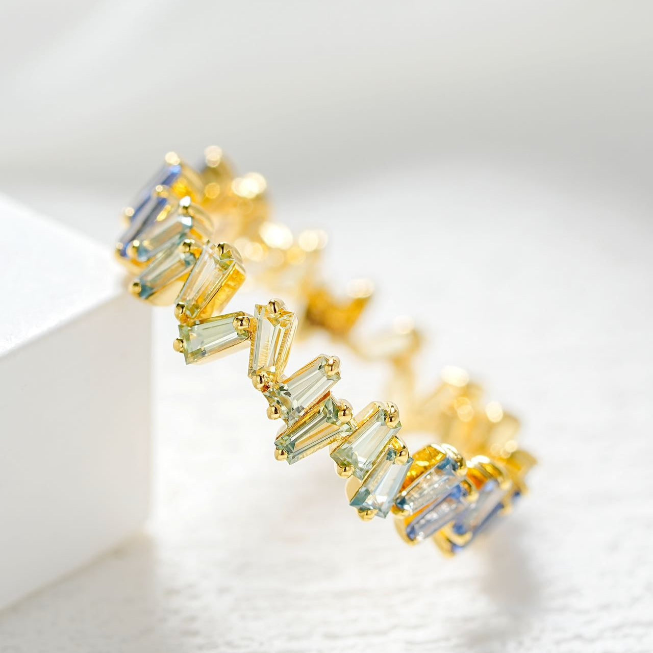 Gold earrings with green gemstones on a light background